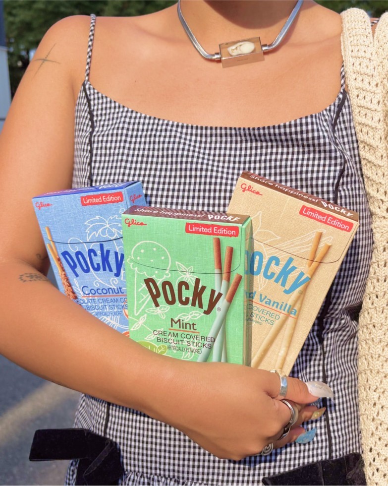 A person holding Pocky Coconut, Mint, and Salted Vanilla boxes in their arm.